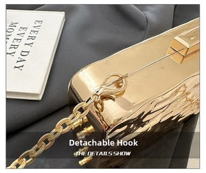 Close-up of golden evening bag with hammered metal texture and detachable chunky chain strap