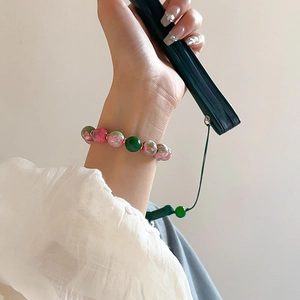 Elegant Chinese style bracelet with green glass beads and gold spacers on a model's wrist