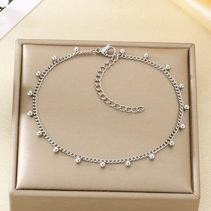 Detail of silver bead anklet chain with lobster clasp on a gold silk background