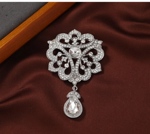 Detailed close-up of a silver vintage court-style brooch with white zircons and teardrop pendant
