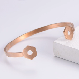 Detailed view of rose gold C-shaped cuff with industrial hexagonal nut ends and brushed finish