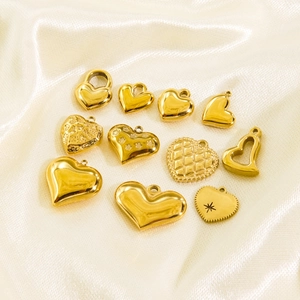 Collection of 11 gold heart-shaped stainless steel pendants on elegant silk background