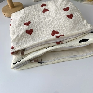 Close-up of smooth metal zipper on textured canvas pouch with heart print pattern