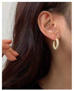 Close-up of elegant gold U-shaped earrings with zircon inlay worn by a female model