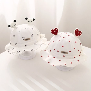 Détail de chapeaux de soleil pour bébé avec motifs panda et cœur, étiquette en cuir
