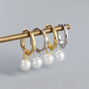 Detail view of gold and silver S925 sterling silver hoop earrings with pearl charms