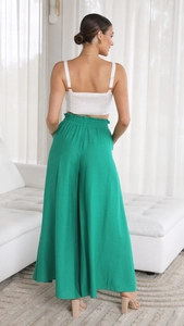 Rear view of woman wearing high-waisted green wide-leg trousers and white tank top