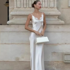 Elegante abito lungo in raso bianco con pizzo indossato da una modella in un contesto classico