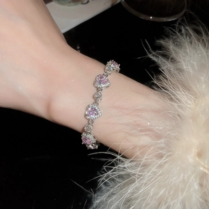 Close-up of pink heart-shaped gemstone bracelet on wrist with elegant feathers