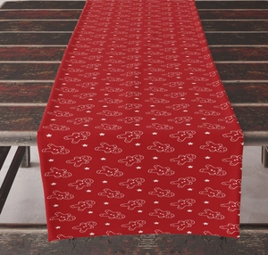 Detailed close-up of red Christmas table runner with gingerbread man and star prints