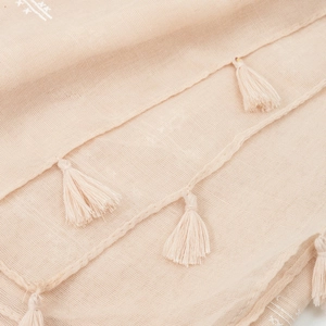 Detail shot of beige cotton linen scarf featuring soft texture and tassel fringe edge