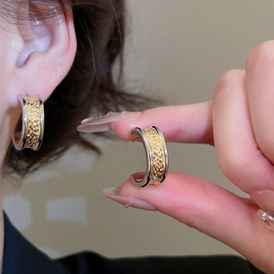Detail of C-shaped mixed metal earrings with textured gold and polished silver finish