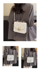 Detailed back view of white quilted crossbody bag with gold round lock and metal strap