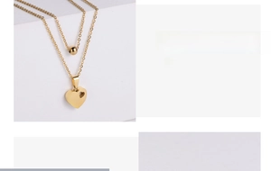 Macro detail of gold-plated double-layer necklace with love engraved heart pendant