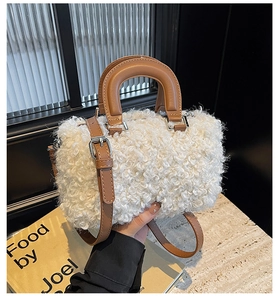 Close-up of white faux shearling box bag with brown leather handles and silver hardware