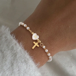 Gros plan détaillé d'un bracelet en perles avec breloque cœur lettre M et croix dorée