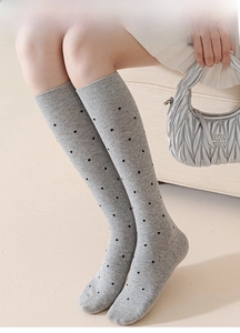 Detail view of light grey knit over-the-knee socks with black polka dots and soft texture