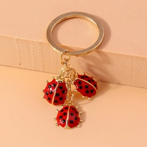 Detailed close-up of three red enamel ladybug charms on a golden metal keychain