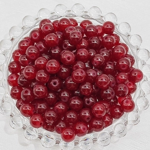 Macro view of 4-8mm deep red glass round beads for DIY jewelry making in a glass bowl