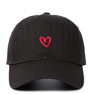 Close-up of red heart embroidery detail on a black soft-top baseball cap surface