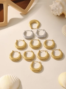 Flat lay of textured gold and silver hoop earrings with honeycomb patterns on beige decor
