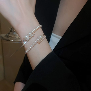 Detail of layered pearl open bangle with zircons on model wearing black suit