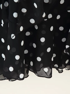 Detailed close-up of lightweight black polka dot chiffon fabric with ruffle hem finish