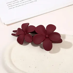 Detail of matte burgundy hair clip featuring a dual flower design on ceramic plate