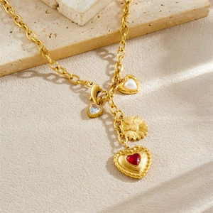 Golden necklace with white, red and sunflower heart charms on elegant stone texture background