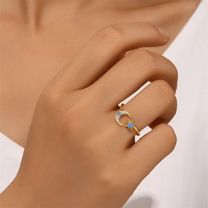 Close-up of a model wearing a gold star and moon ring with blue opal and zircon stones