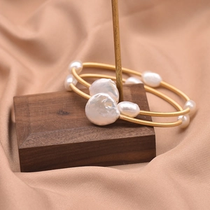 Macro shot of handcrafted double-layer baroque pearl bracelet on golden wire and silk