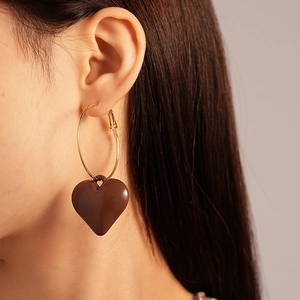Close-up of vintage heart drop earrings on model showing glossy brown finish and hoop