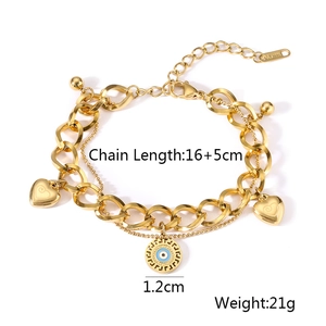 Detail of gold evil eye and heart charms on a layered stainless steel chain bracelet