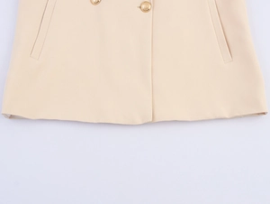 Detail view of beige blazer featuring polished gold buttons and smooth fabric texture