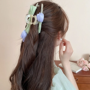 Detail view of a large purple tulip hair claw clip holding long hair in a bun