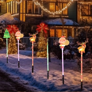 Solar Christmas path lights with Santa and Reindeer glowing on outdoor snowy garden lawn