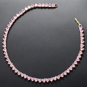 Macro shot of gold necklace featuring sparkling pink heart-shaped crystal pendant details