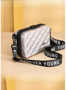Detail view of silver hard shell mini crossbody bag with diamond pattern and logo strap