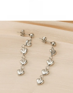 Vue détaillée de boucles d'oreilles pendantes coeur argent sur tissu en soie dorée