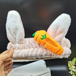 Detailed close-up of a plush pink and white headband with rabbit ears and carrot decor