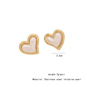 Macro shot of gold heart-shaped stainless steel earrings with imitation pearl inlays