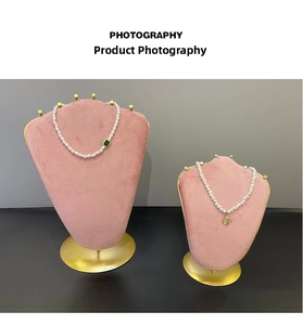 Close-up of pearl necklaces with emerald and opal pendants on pink velvet displays