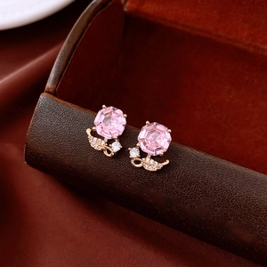 Détail macro de boucles d'oreilles octogonales en zircon rose sur boîte en cuir