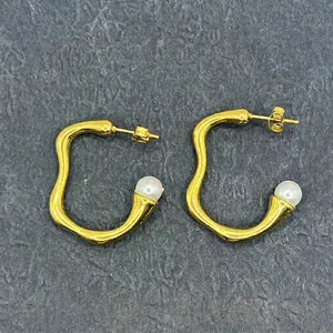 Detail of vintage 18k gold plated wave earrings featuring round white pearls