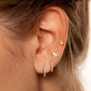 Close-up of golden S925 silver geometric earrings with sparkling diamonds on a model ear