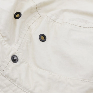 Close-up of beige sun hat fabric showing metal air vents and sturdy silver snap buttons