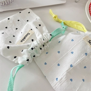 Close-up of cotton drawstring storage bags featuring black and blue heart patterns