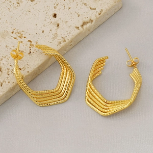 Minimalist textured gold multi-layer U-shaped earrings on stone and grey fabric background