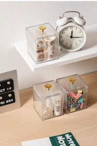 Detailed view of three acrylic storage boxes with gold clover handles and ribbed texture