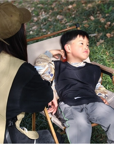 Waterproof black kids apron vest worn by a child in an outdoor camping activity